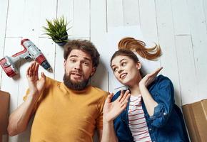 happy man and woman lie on the floor a flower in a pot planning future renovation work photo