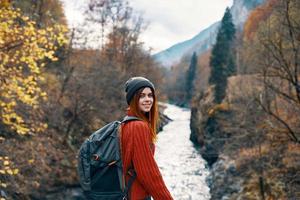 alegre mujer turista de todas el ley admira el naturaleza de el montaña río foto
