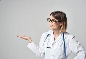 woman nurse in a medical gown gesturing with her hands on a light background copy space photo