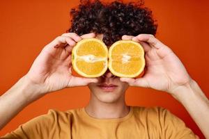 guy with curly hair oranges near face emotions close-up photo