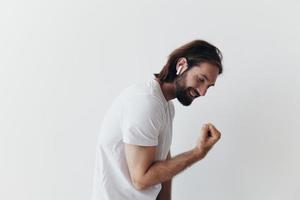contento hombre escuchando a música y sonriente en un blanco camiseta en un blanco antecedentes contento foto