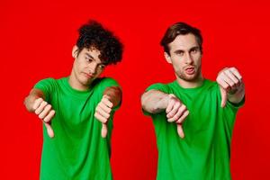 Cheerful friends in green t-shirts gesturing with hands isolated background photo