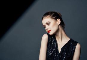 Side view of beautiful woman in black dress with hairstyle photo