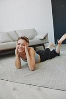 Teenage girl lying on the floor at home smiling in home clothes with a short haircut, lifestyle without filters, free copy space photo