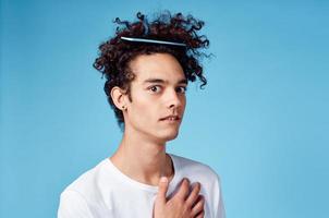 a man with a comb in his hair gesturing with his hands on a blue background Copy Space photo