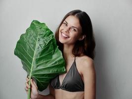 cheerful pretty woman in swimsuit and green leaf cropped view Exotic clean skin photo