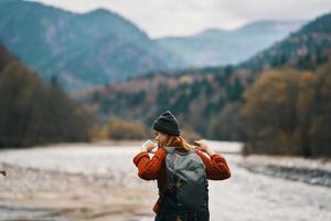 joven mujer en el río banco con mochila turismo modelo viaje montañas foto