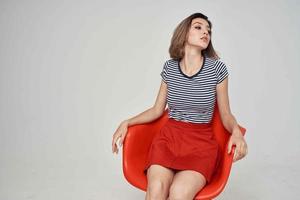 woman in a striped T-shirt sitting on the red chair modern style hairstyle photo