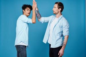 Happy friends in identical shirts shake hands on a blue background communication photo