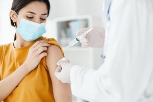 patient in a medical mask looks at the doctor with a syringe in hand vaccination photo