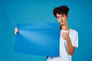 Cheerful guy with curly hair and blue mockup poster advertising photo
