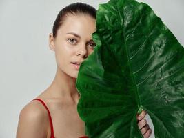 cosmetology dermatology beautiful woman with palm leaf and red t-shirt model photo