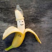 Banana with condom on the old wooden background. photo