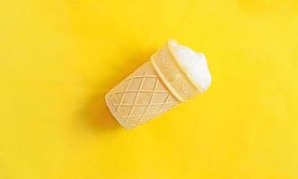 Vanilla ice-cream in a waffle cup on yellow background photo