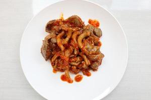 chicken liver, gizzard and chicken intestine cooked with spices, turmeric, and chilies served on a white plate, isolated on white photo