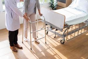 caucasian man doctor is examining the female older patient in wheelchair the hospital. photo