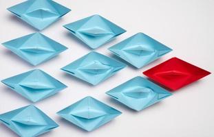 Group of paper boats on a white background.Concept of a strong leader in a team, manipulation of the masses, following new perspectives, collaboration and unification. photo