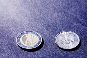 Two coins euro and ruble on dark background in sunlight, heads and tails photo