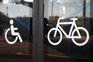 Signs of disabled person and bicycle on bus doors closeup photo
