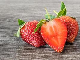 close up of three strawberries on a wooden table photo