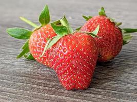 close up of three strawberries on a wooden table photo