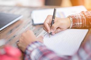 Mañana ligero mano escritura en cuaderno monedas y alarma reloj para antecedentes foto