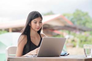 joven mujer vistiendo reloj inteligente utilizando ordenador portátil computadora. hembra trabajando en ordenador portátil foto