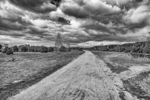 primavera paisaje con un suciedad camino, campos, arboles y cielo con nubes en Polonia foto