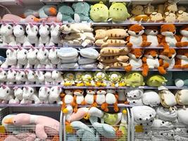 Various kinds of cute animal character dolls are on the sale rack in a shop photo