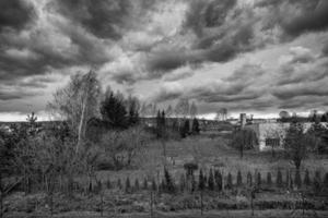 autumn landscape with leafless trees and dark clouds in the sky and an old building photo