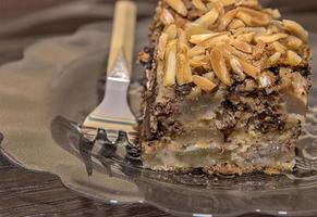 Close view of a delicate piece of chocolate cake, torte with nuts on a plate with a fork. photo