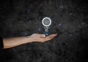 hand holding drawing virtual lightbulb on dark black background for creative and smart thinking idea concept.  new idea concept with innovation and inspiration, innovative technology in science. photo