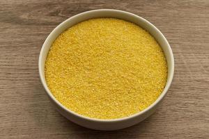 Italian polenta flour in a bowl isolated on wooden background. photo