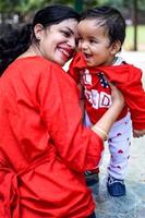 Loving mom carrying of her baby at society park. Bright portrait of happy mum holding child in her hands. Mother hugging her little 9 months old son. photo