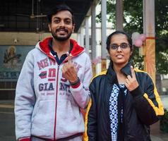 New Delhi, India - December 04 2022 - Unidentified people showing their ink-marked fingers after casting votes in front of polling booth of east Delhi area for MCD local body Elections 2022 photo