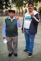 New Delhi, India - December 04 2022 - Unidentified people showing their ink-marked fingers after casting votes in front of polling booth of east Delhi area for MCD local body Elections 2022 photo
