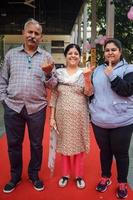 New Delhi, India - December 04 2022 - Unidentified people showing their ink-marked fingers after casting votes in front of polling booth of east Delhi area for MCD local body Elections 2022 photo