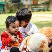 dos contento Niños en sociedad parque, contento asiático hermanos quien son sonriente felizmente juntos. hermanos jugar al aire libre en verano, mejor amigos. niñito bebé chico jugando con su contento hermano en el jardín foto