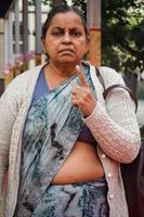 New Delhi, India - December 04 2022 - Unidentified people showing their ink-marked fingers after casting votes in front of polling booth of east Delhi area for MCD local body Elections 2022 photo
