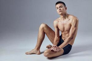 man with a pumped body posing sitting on the floor photo