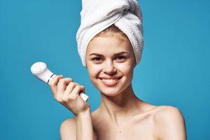 beautiful woman with a towel on her head massager in hands skin care photo