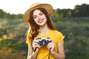 smiling woman in hat with camera in hands yellow t-shirt nature photo