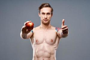 athletic guy with a pumped up torso healthy lifestyle nutrition vitamins red apple photo