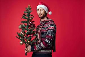 handsome man with a tree in his hands ornaments holiday fun red background photo