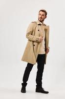 handsome man in beige coat autumn style studio full growth side view photo