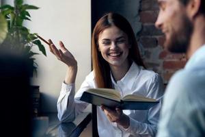 negocio mujer en camisa con libro en manos siguiente a hombre oficina trabajo foto