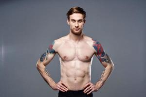 atlético hombre con bombeado arriba abdominales tatuajes en su brazos foto