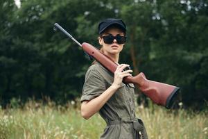 Military woman In dark sunglasses hunting lifestyle weapon green leaves photo