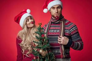 man and woman are standing next to New Years holiday Christmas gifts photo