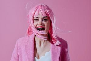 Woman in a pink wig on a pink background laughs, open mouth photo